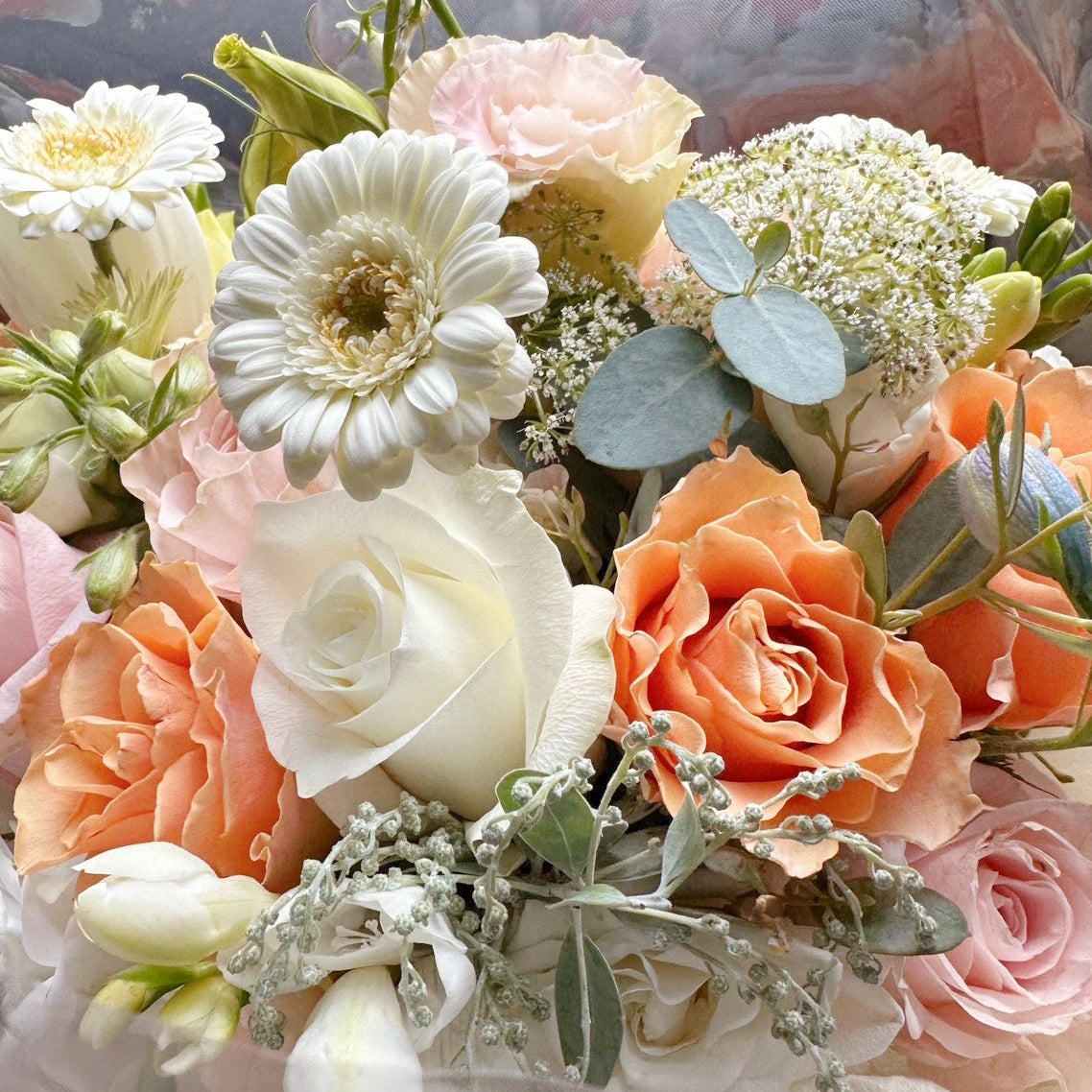 round bouquet in orange and yellow hue, rose, gerbera, freesia, lisianthus